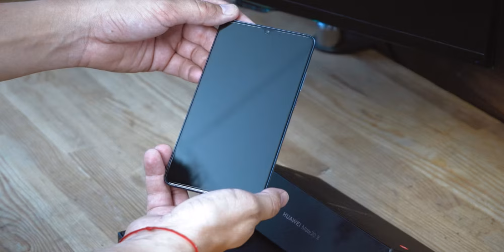 9 روش برای استفاده مجدد از گوشی اندرویدی قدیمی شما 21 a man holding an android phone trying to power it on